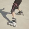 A person performing a T-stop on inline skates, dragging one foot perpendicular to their direction of travel to slow down